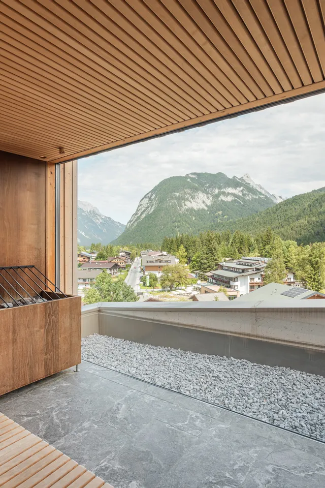 Moderne Holzsauna mit Panoramablick auf Berglandschaft und alpines Dorf