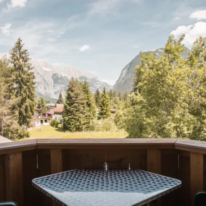 Balkon mit Tisch und Stühlen mit Blick auf Alpen-Tal und Kiefernwälder