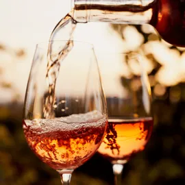 Roséwein wird bei Sonnenuntergang im Freien in ein Glas eingeschenkt