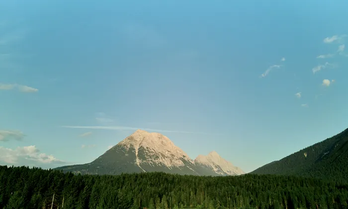 Gebirgszug mit bewaldeten Hängen unter klarem blauen Sommerhimmel