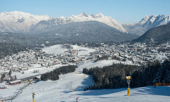 Schneebedeckter Skiort in den Alpen mit Skipisten und Bergpanorama