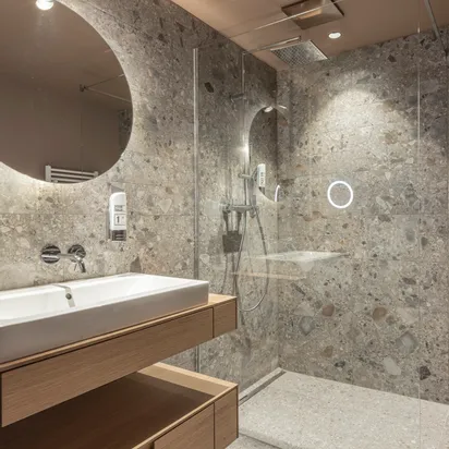 Modern bathroom with stone-tiled walls, walk-in shower and wood vanity with rectangular sink