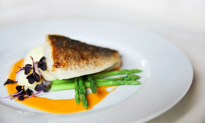 Gegrilltes Fischfilet mit Spargel, Kartoffelpüree, Microgreens und orangener Sauce serviert