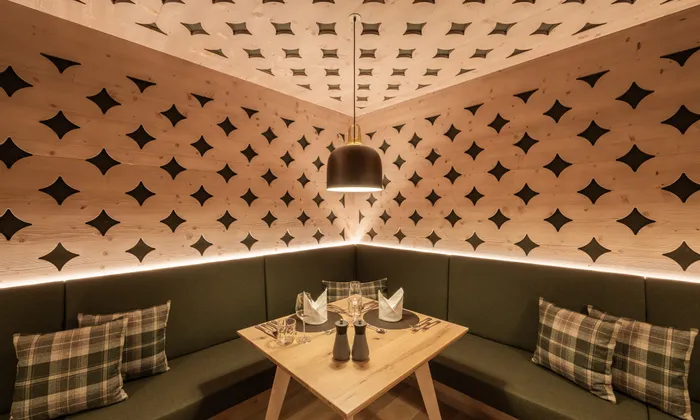 Gemütliche Restaurantecke mit Holzwänden, grüner Sitzbank und moderner Hängeleuchte