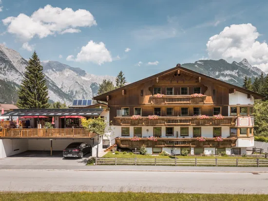 Alpenhotel mit blumengeschmückten Balkonen und Bergblick unter blauem Himmel
