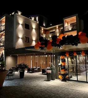 Moderner Hoteleingang mit orangefarbenen und schwarzen Ballondekorationen bei Nacht