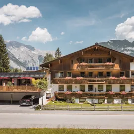 Alpenhotel mit blumengeschmückten Balkonen und Bergblick unter blauem Himmel