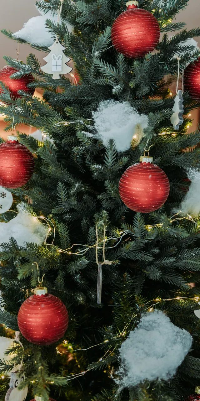 Decorated Christmas tree with red baubles, faux snow and white ornaments in cozy indoor setting