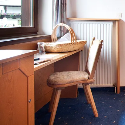 Gemütliches Einzelzimmer im Hotel mit Holzmöbeln, Schreibtisch, Bett und Badezimmer