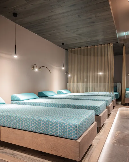 Modern spa relaxation room with turquoise beds and ambient lighting