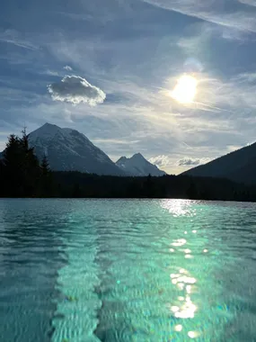 Reflective infinity pool with mountain backdrop at sunset in the Alps