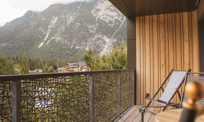 Wooden balcony with lounge chairs overlooking Alpine mountain landscape