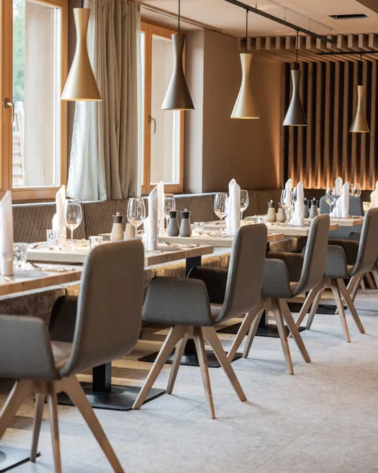 Modernes Restaurant mit Holztischen, grauen Stühlen und eleganter Hängebeleuchtung