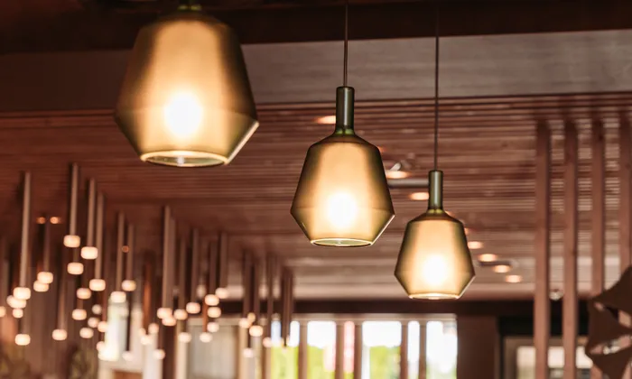 Modern pendant lights hanging from wooden ceiling in stylish interior
