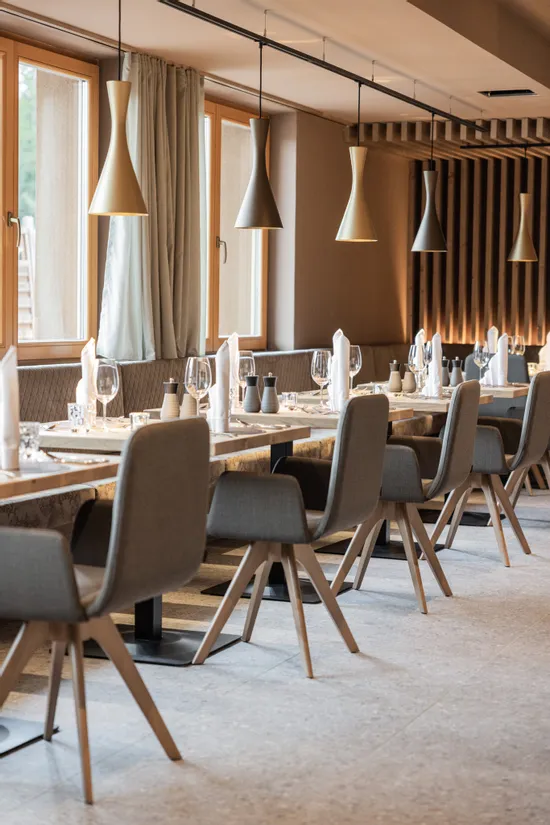 Modernes Restaurant mit Holztischen, grauen Stühlen und eleganter Hängebeleuchtung