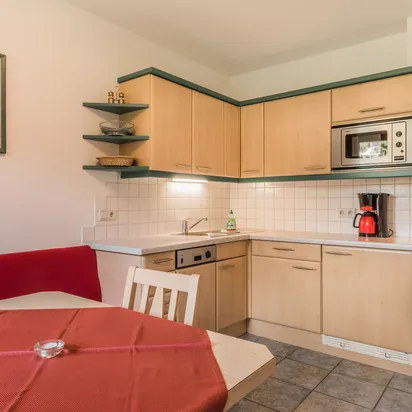 Cozy kitchen with light wood cabinets, red bench seating, and modern appliances