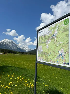 Wanderkarte von Seefeld auf einer Almwiese mit schneebedeckten Bergen im Hintergrund