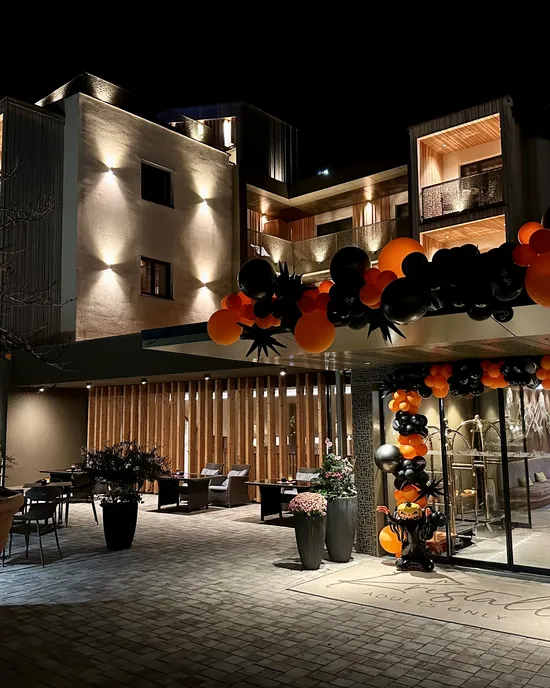 Moderner Hoteleingang mit orangefarbenen und schwarzen Ballondekorationen bei Nacht