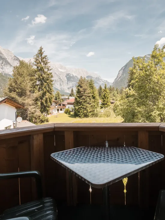 Balkon mit Tisch und Stühlen mit Blick auf Alpen-Tal und Kiefernwälder