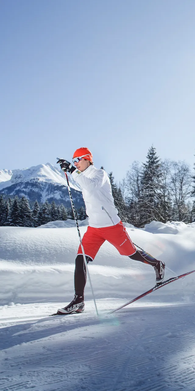 Two people cross-country skiing on a sunny winter day in a snowy mountain landscape