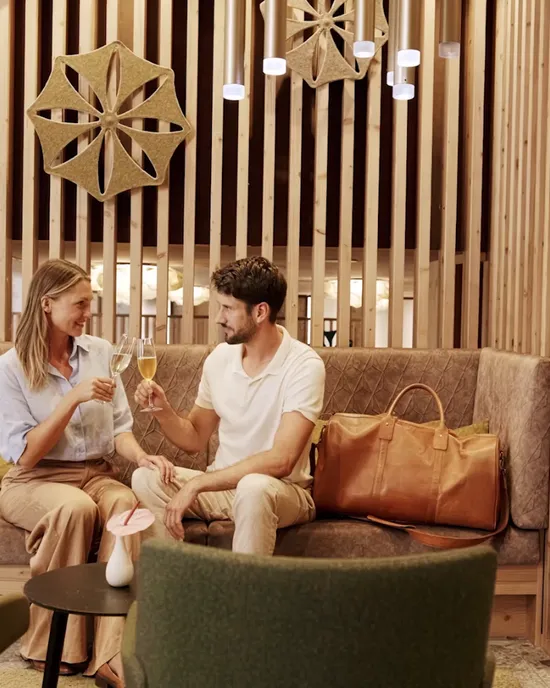 Couple toasting with champagne in modern hotel lounge with wooden decor