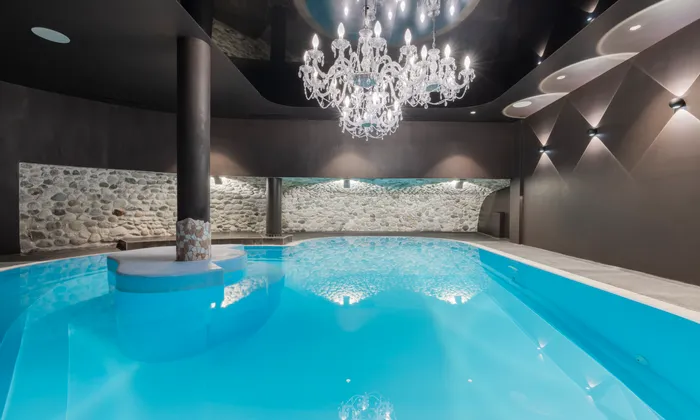 Luxuriöser Innenpool mit Kronleuchterbeleuchtung und Akzenten aus Steinwänden