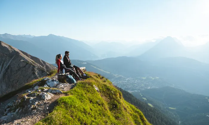 Wanderer entspannen auf Bank mit Blick auf alpines Tal und Berglandschaft