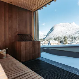 Moderne Holzsauna mit Bergblick und verschneitem Dorf im Außenbereich