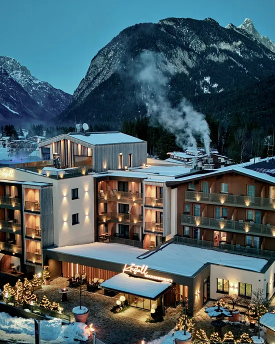 Luxury hotel Kristall in snow-covered alpine village at twilight with mountain backdrop