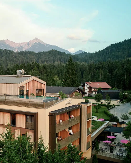 Modernes Alpenhotel im bewaldeten Bergdorf mit malerischer Bergkulisse im Hintergrund