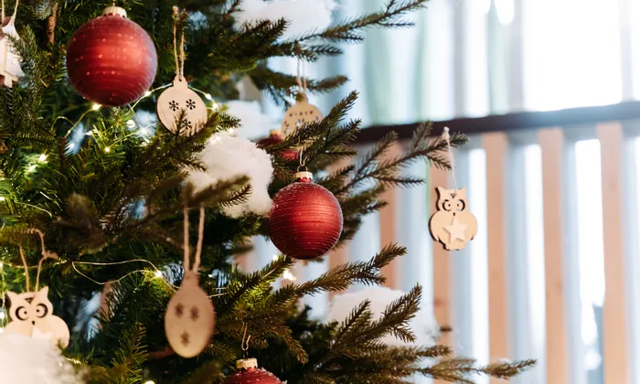 Geschmückter Weihnachtsbaum mit roten Kugeln, Holzanhängern und Lichterkette