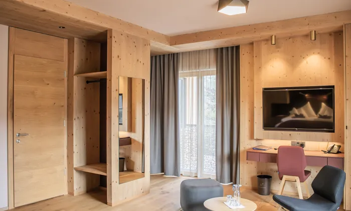 Modernes Hotelzimmer mit Holzeinrichtung, Flachbildfernseher, Schreibtisch und Sitzecke