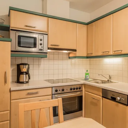 Modern wooden kitchen with built-in appliances, coffee machines, and tiled backsplash
