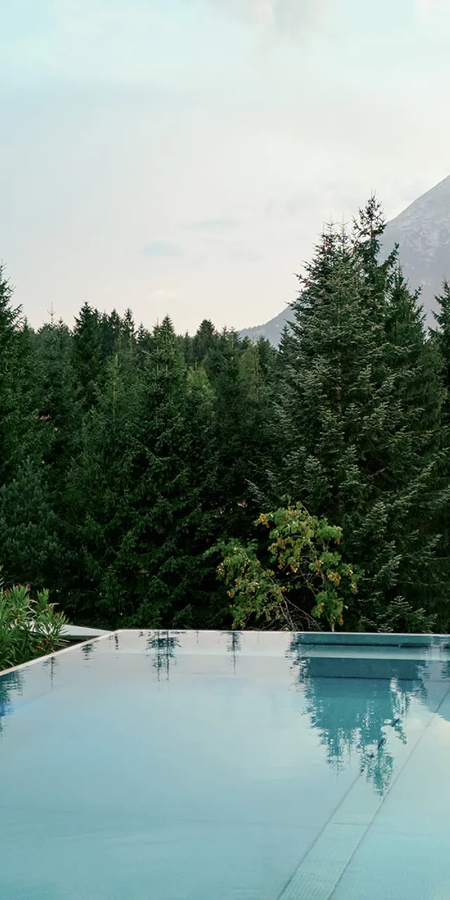 Infinity-Pool neben Holzlodge mit Blick auf Pinienwald und Berglandschaft