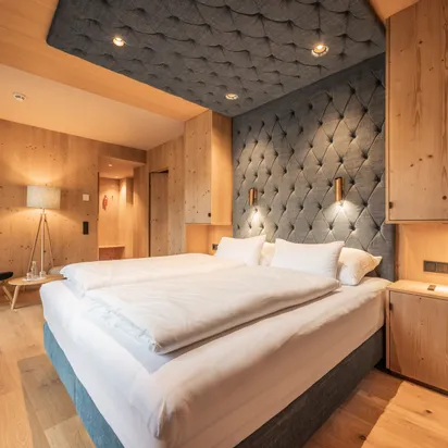 Modernes Hotelzimmer mit Holzeinrichtung, Doppelbett und gemütlicher Beleuchtung