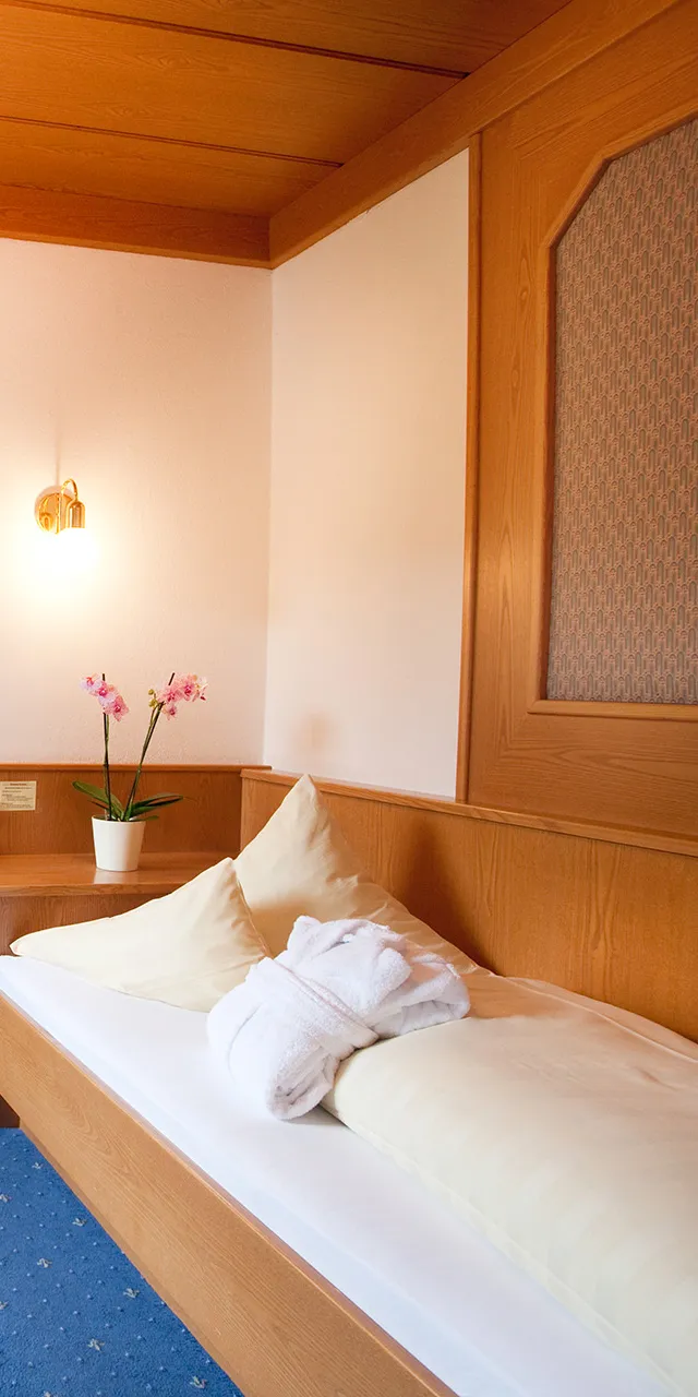 Gemütliches Einzelzimmer im Hotel mit Holzmöbeln, Schreibtisch, Bett und Badezimmer