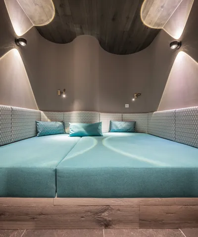Modernes Wellness-Liegebett mit türkisen Kissen und stimmungsvoller Beleuchtung im Spa-Raum