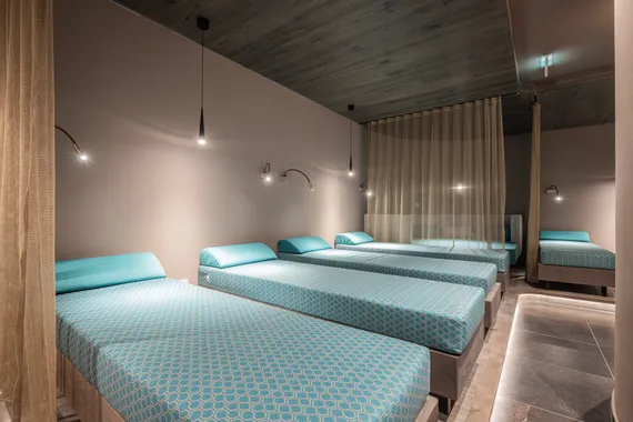 Moderner Spa-Ruheraum mit blauen Polsterliegen und sanfter Ambientebeleuchtung
