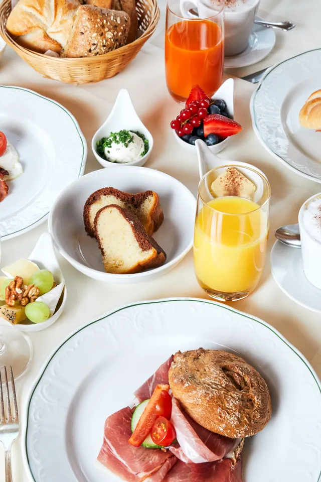 Elegant European breakfast with cold cuts, fresh bread, fruit, juices, coffee, and pastries on white table setting