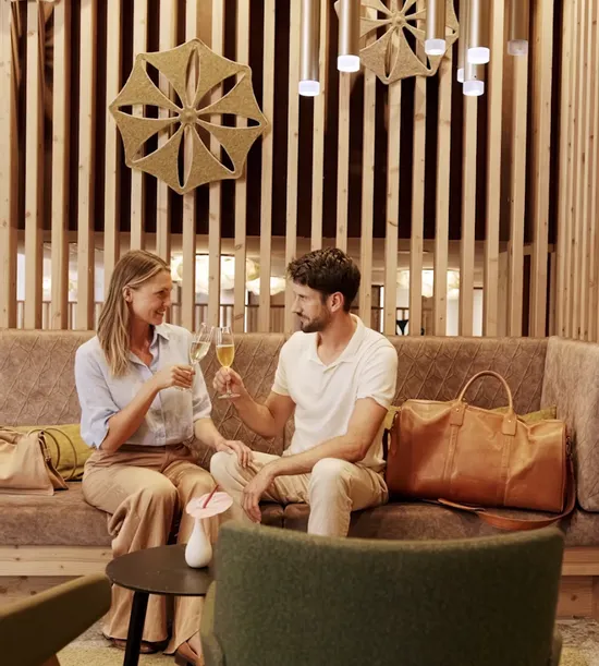 Paar stößt mit Champagner in moderner Hotellounge mit Holzdekor an