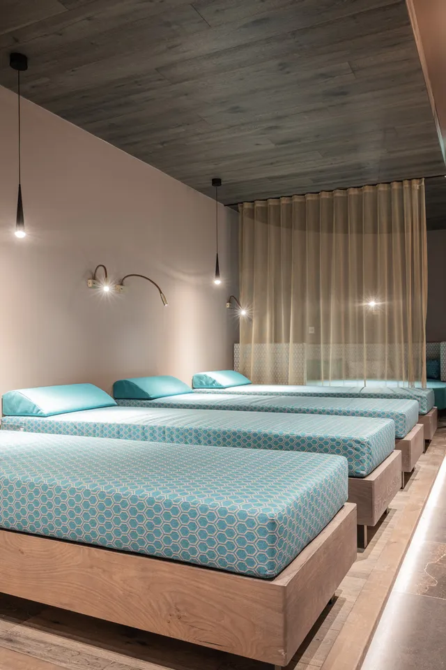 Modern spa relaxation room with turquoise beds and ambient lighting