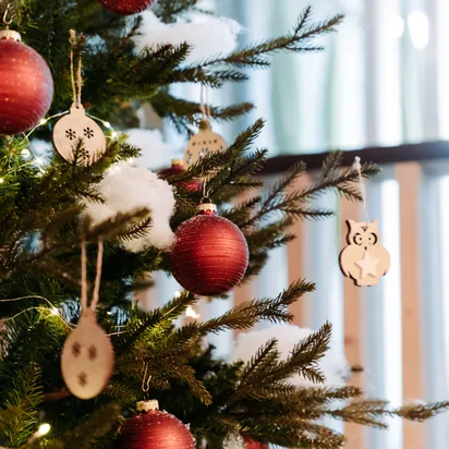 Geschmückter Weihnachtsbaum mit roten Kugeln, Holzanhängern und Lichterkette