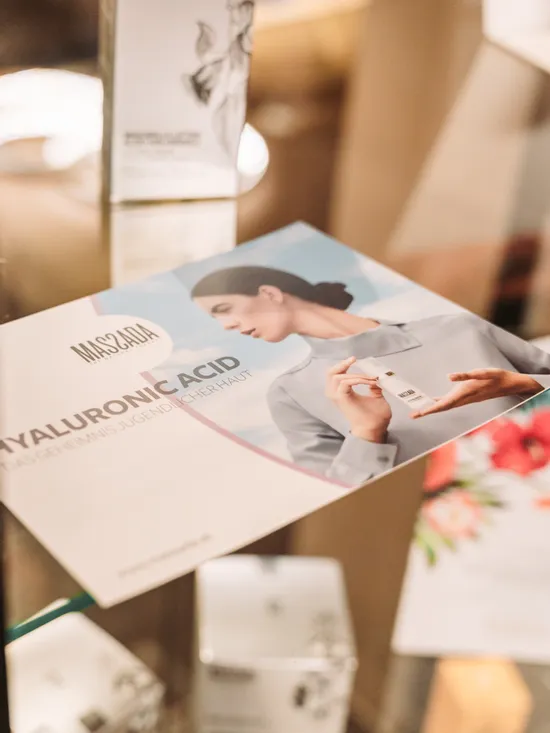 Hyaluronic acid skincare product brochure with woman holding serum bottle in glass display