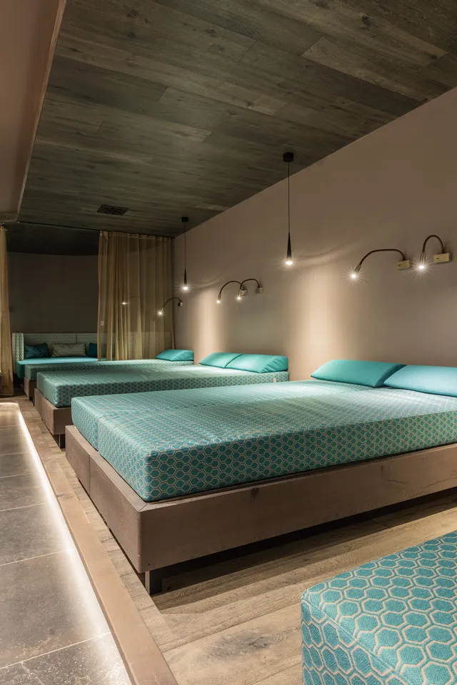 Modern spa relaxation room with multiple teal lounge beds and ambient lighting