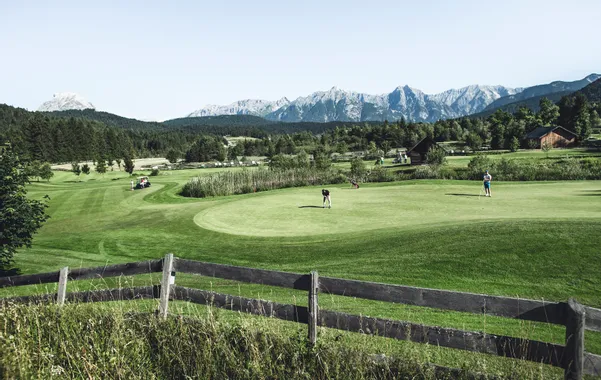 Golfspieler auf einem malerischen Golfplatz mit Bergblick und grüner Landschaft