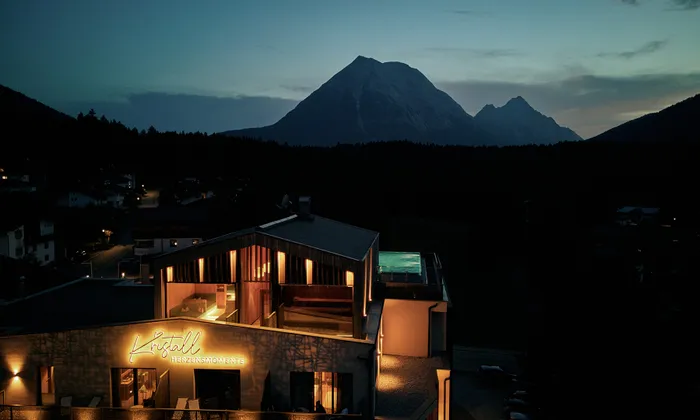 Kristall Herzensmomente hotel glowing at dusk with mountain backdrop in Seefeld