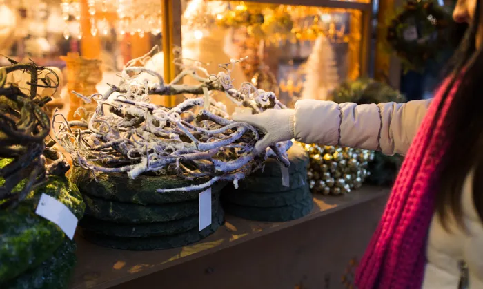 Person examining frosted decorative wreaths at a Christmas market stall