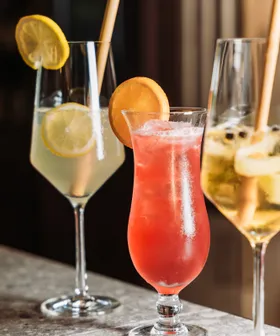 Refreshing summer cocktails with citrus slices and bamboo straws on a bar counter