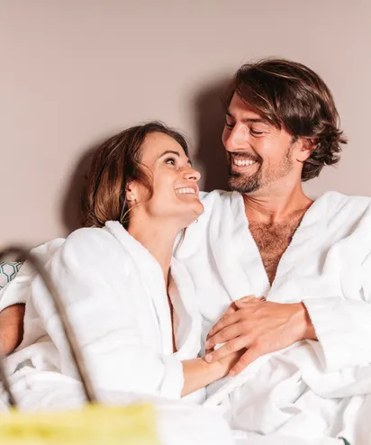 Happy couple in white bathrobes relaxing together at a spa or wellness retreat