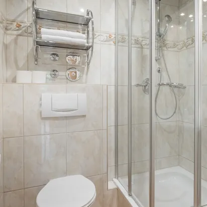 Modern hotel bathroom with glass shower, wall-hung toilet, and white vanity sink